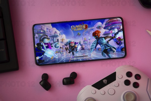 Dhaka, Bangladesh- 15 July 2025: A close-up of a gamepad with the Clash of clans seen on smartphone