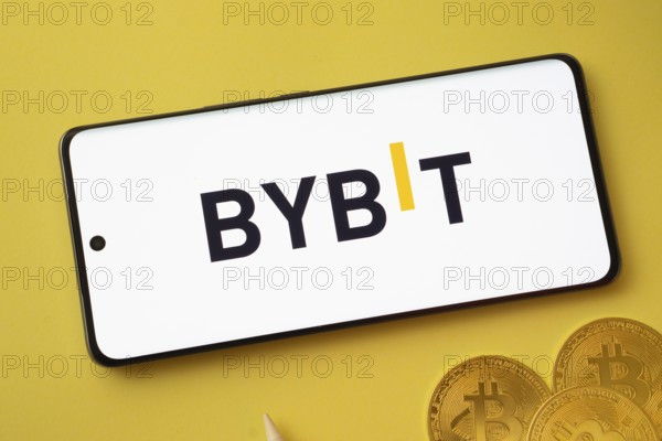 Dhaka, bangladesh- 12 July 2025: Bybit logo displayed on a smartphone with Bitcoin coins on a yellow background