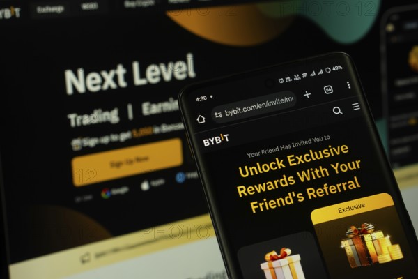 Dhaka, Bangladesh - 15 July 2025: The logo of Bybit is displayed on a smartphone screen, and the website the bybit is visible on a computer screen in the background