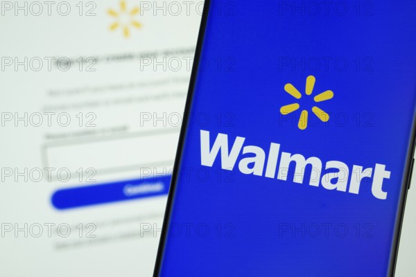 Dhaka, Bangladesh- 15 July 2025: Walmart logo is displayed on a smartphone screen, with the walmart login page visible on a computer screen in the background