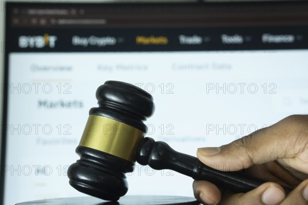 Dhaka, Bangladesh- 20 June 2025: A hand holds a gavel in front of a computer screen displaying Bybit's website