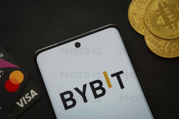 Dhaka, Bangladesh- 15 July 2025: Smartphone displaying Bybit logo surrounded by Bitcoin coins and payment cards