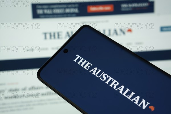 Dhaka, Bangladesh - 18 March 2025: The logo of The Australian is displayed on a smartphone screen, and the website is visible on a computer screen in the background
