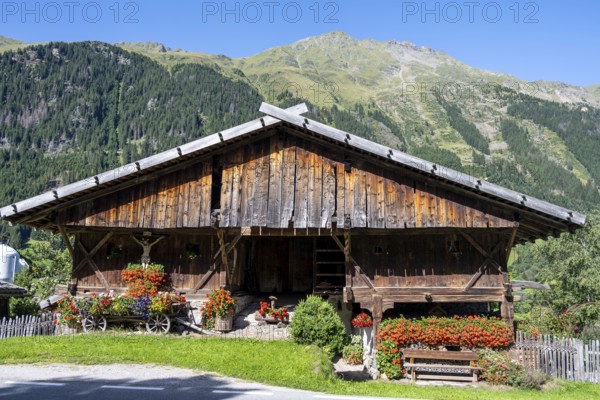 Colourful floral decorations and crucifix at a rustic alpine hut, Ridnauntal, South Tyrol, Italy