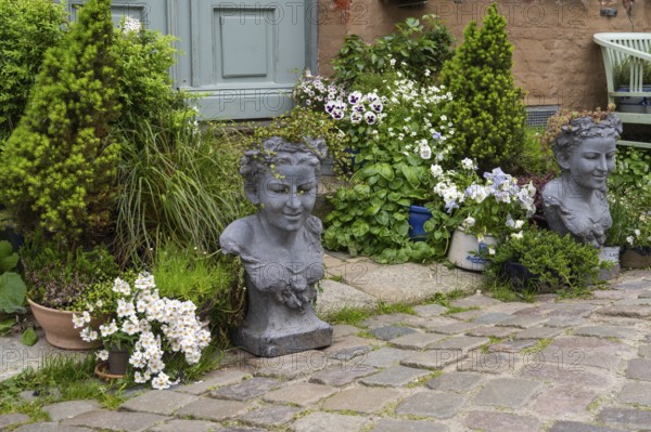 House entrance with blooming flowers, conifers and stone busts, Old Town, Husum, North Frisia, Schleswig-Holstein, Germany