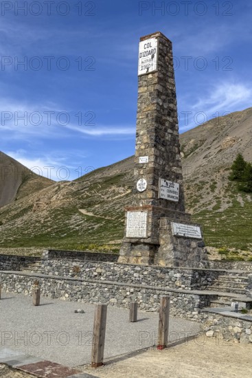 At Alpine pass Col de l'Izoard d'Izoard 2360 metres high road pass at pass summit of mountain road pass road 1934 erected altitude marker monument stele memorial column made of natural stone in memory of dedicated to General Baron Berge and workers of road construction, Cervières, Department Hautes-Alpes, Provence-Alpes-Cote d'Azur, France