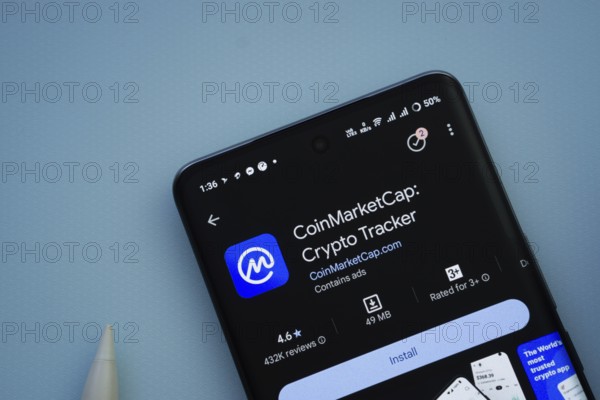 Dhaka, Bangladesh- 29 May 2025: On a blue surface, a smartphone displays the Coinmarketcap app within the Google Play Store