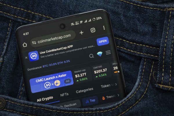 Dhaka, Bangladesh- 15 June 2025: A smartphone displaying the Coinmarketcap.com web interface peeks out of a denim pocket