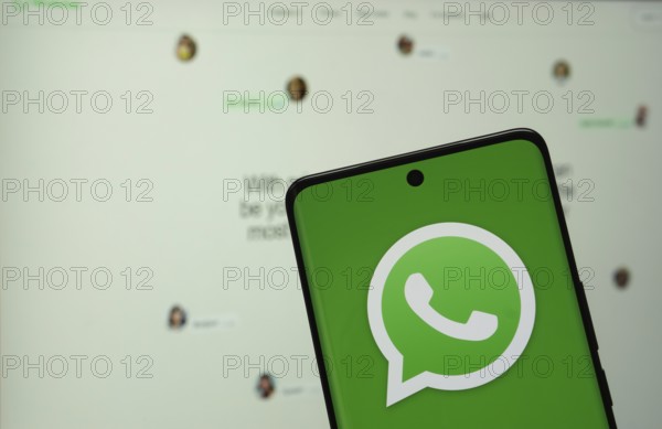 Dhaka, Bangladesh - 04 July 2025: The logo of the WhatsApp is displayed on a smartphone screen, and the website is visible on a computer screen in the background
