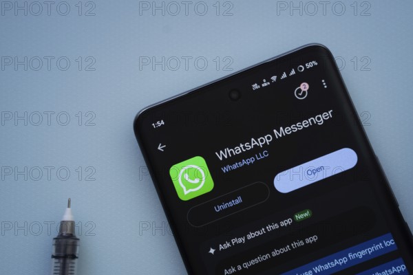 Dhaka, Bangladesh- 29 May 2025: On a blue surface, a smartphone displays the WhatsApp Messenger app within the Google Play Store