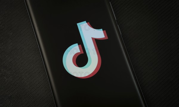 The logo of the TikTok is displayed on a smartphone screen