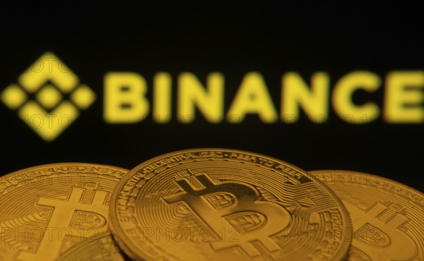Dhaka, Bangladesh- 22 June 2025: Close-up of Bitcoin coins with the Binance logo visible on a screen in the background