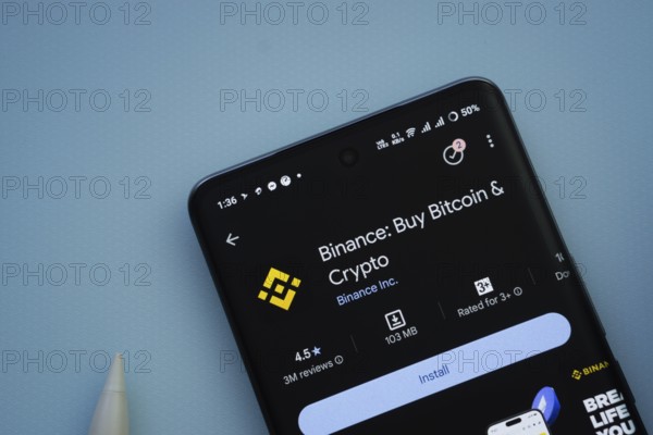 Dhaka, Bangladesh- 29 May 2025: On a blue surface, a smartphone displays the binance app within the Google Play Store