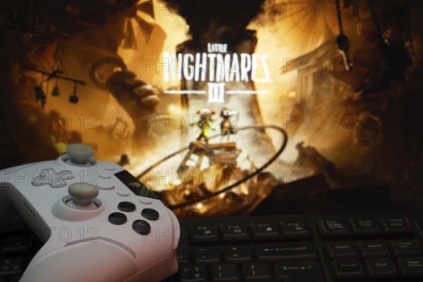 Dhaka, Bangladesh- 22 July 2025: A close-up of a gamepad with the little nightmares 3 seen on screen in the background. Little Nightmares III is an upcoming horror adventure video game