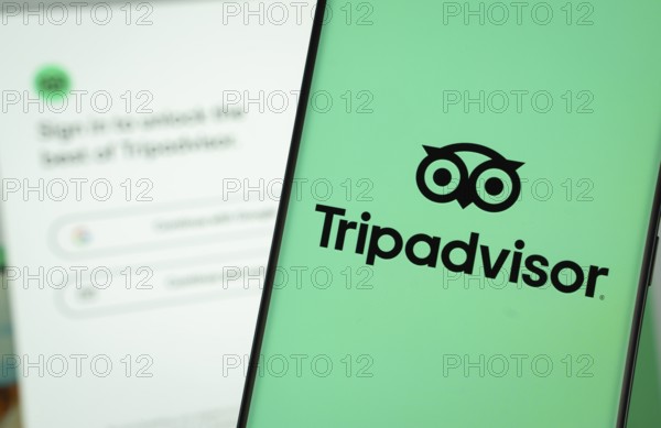 Dhaka, Bangladesh- 22 June 2025: Tripadvisor logo is displayed on a smartphone screen, with the tripadvisor login page visible on a computer screen in the background