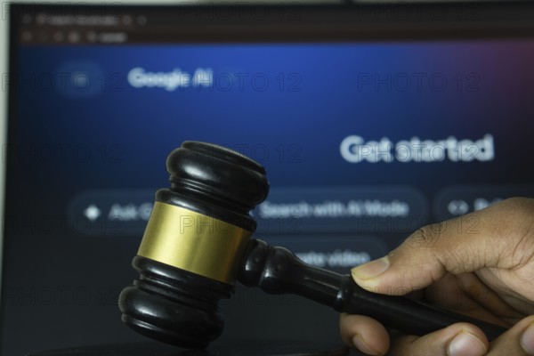 A hand holds a gavel in front of a computer screen displaying Google AI's website