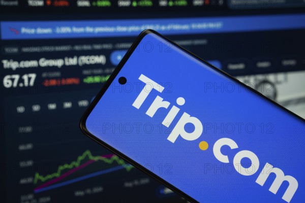 trello logo is displayed on a smartphone screen, with a stock graph webpage visible on a computer screen in the background