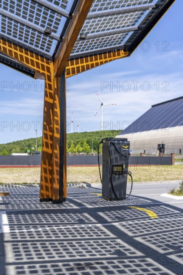 Electric charging station on the site of the former Lohberg colliery in Dinslaken, operated by Fastned, uses electricity from wind power and solar energy, fast-charging columns, with its own solar roof, in the background the 11, 500 square metre solar roof on the colliery's former coal mixing hall, wind farm on the Lohberg slagheap, North Rhine-Westphalia, Germany
