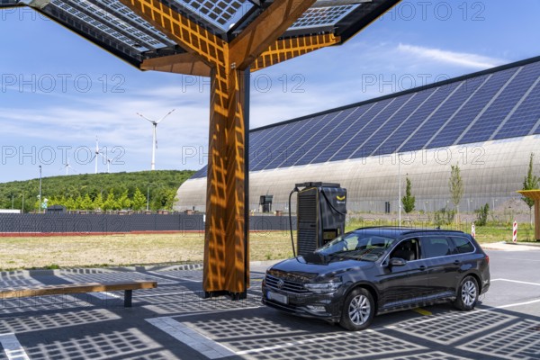 Electric charging station on the site of the former Lohberg colliery in Dinslaken, operated by Fastned, uses electricity from wind power and solar energy, fast-charging columns, with its own solar roof, in the background the 11, 500 square metre solar roof on the colliery's former coal mixing hall, wind farm on the Lohberg slagheap, North Rhine-Westphalia, Germany
