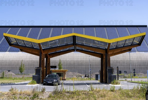 Electric charging station on the site of the former Lohberg colliery in Dinslaken, operated by Fastned, uses electricity from wind power and solar energy, fast-charging columns, with its own solar roof, in the background the 11, 500 square metre solar roof on the colliery's former coal mixing hall, North Rhine-Westphalia, Germany