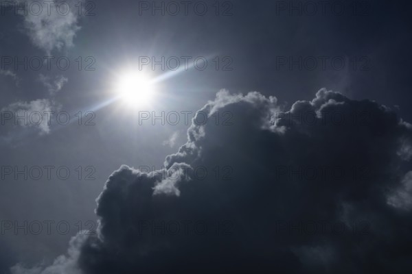 Bright sun shining through dark dramatic clouds against an atmospheric sky