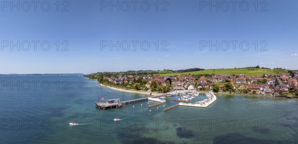 Luftbild, Panorama von der Bodenseegemeinde Hagnau, Winzerdorf und beliebter Ferienort am Bodensee, dahinter Rebhänge, auf denen hauptsächlich die Weinsorten Müller Thurgau und Blauer Burgunder angebaut werden. Am Seeufer der am 23.Mai 2025 eingeweihte, neue Westhafen, Yachthafen mit der Schiffanlegestelle, Bodenseekreis, Baden-Württemberg, Deutschland