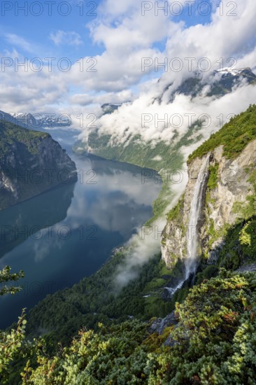 Gjerdefossen waterfall, at Ørnesvingen viewpoint, atmospheric clouds over the fjord in the morning light, at Geirangerfjord, near Geiranger, Møre og Romsdal, Norway