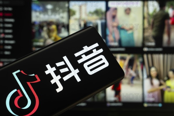 Dhaka, Bangladesh - 18 March 2025: The logo of the tiktok is displayed on a smartphone screen, and the website tiktok is visible on a computer screen in the background