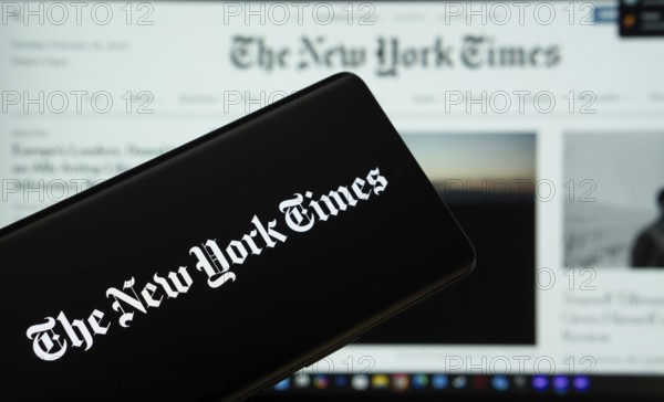 Dhaka, Bangladesh - 18 March 2025: The logo of the the new york times is displayed on a smartphone screen, and the website the new york times is visible on a computer screen in the background