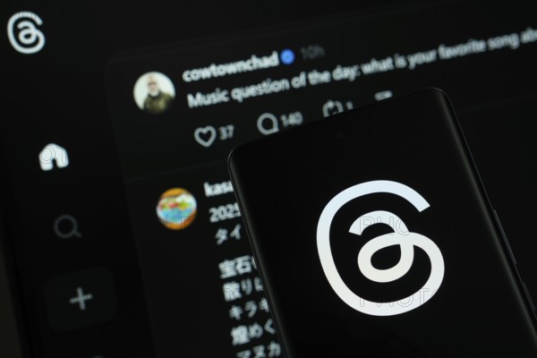 Dhaka, Bangladesh - 18 March 2025: The logo of the threads is displayed on a smartphone screen, and the website threads is visible on a computer screen in the background