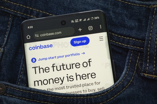 Dhaka, Bangladesh- 15 June 2025: A smartphone displaying the coinbase.com web interface peeks out of a denim pocket