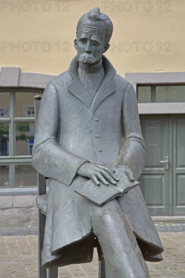 Monument to philosopher Friedrich Nietzsche, bronze sculpture, modern art, standing female figure, girl, sitting on chair, communication, conversation, listening, book, Holzmarkt, Saale, Naumburg, Saxony-Anhalt, Germany