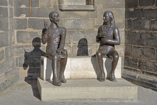 Sculpture Schütz-Novalis Bench by Steffen Ahrens and Grit Berkner 2022, composer Heinrich Schütz, writer Novalis Friedrich von Hardenberg, bench, monument, modern art, two, bronze sculptures, sitting, communication, interaction, pointing finger, listening, telling, talking, market square, Weißenfels, Saxony-Anhalt, Germany