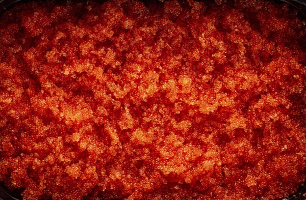 Container with orange caviar, flying fish, Tobiko, on the table, caviar for rolls and sushi, close-up