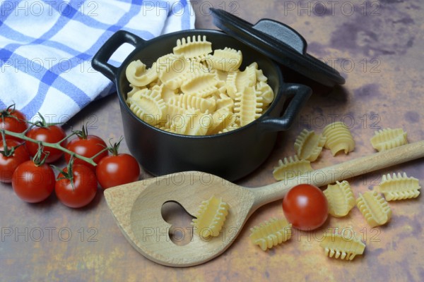 Italian pasta, Radiatori variety, in pots and heart-shaped cooking spoon
