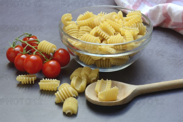 Italian pasta in glass bowl and cooking spoon, Radiatori variety