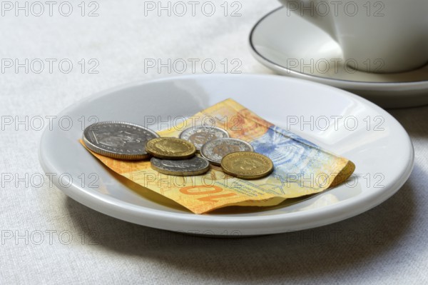 Tip, Swiss coins and Swiss franc note on plate, Switzerland