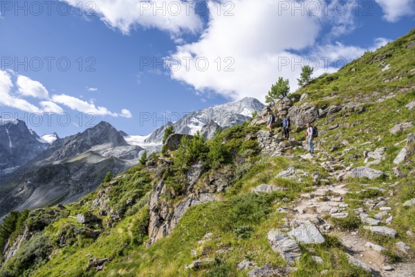 Three mountaineers on a hiking trail, mountain landscape near Arolla, behind mountain peak Mont Collon and glacier Glacier de Tsijore Nouve, Valais, Western Alps, Switzerland