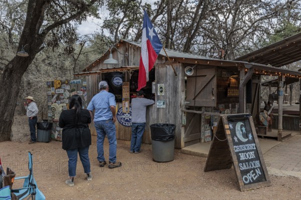 Tourists buying beer at an open-air bar in Luckenbach, Texas, USA
