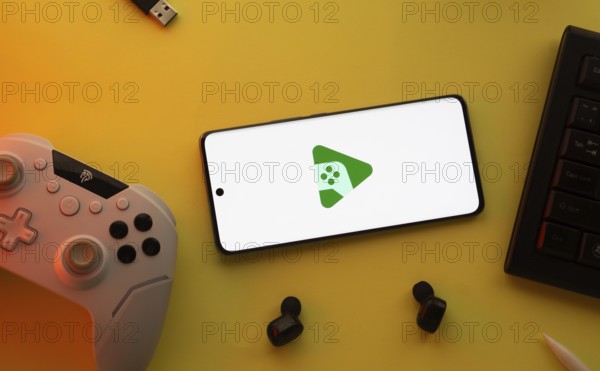 Smartphone with Google Play Games logo, game controller, and earbuds on a yellow background