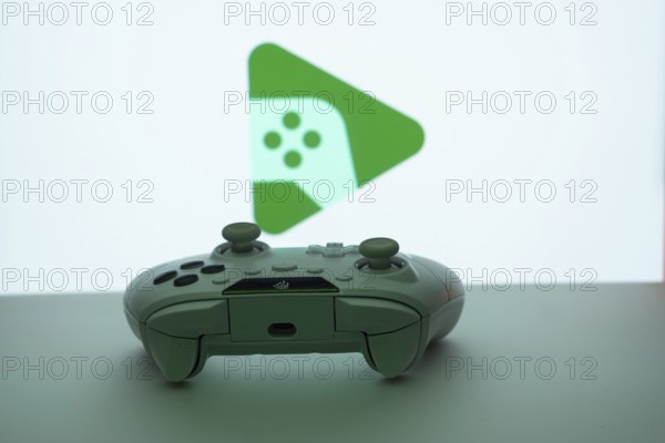 A close-up of a gamepad with the Google Play Games seen on screen in the background