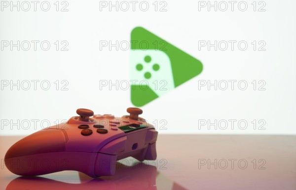 A close-up of a gamepad with the Google Play Games seen on screen in the background