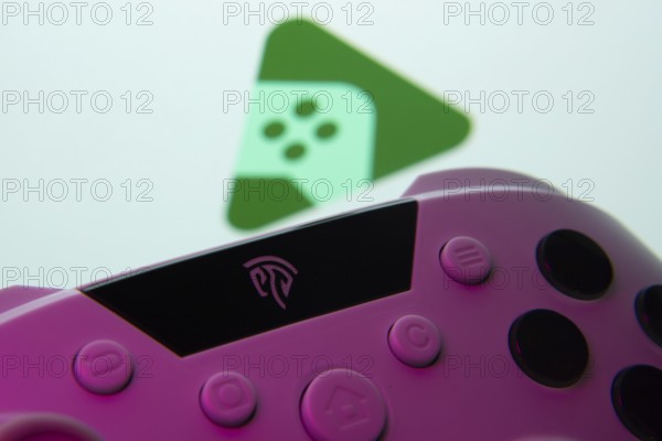 A close-up of a gamepad with the Google Play Games seen on screen in the background