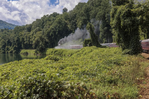 Steam from the Great Smoky Mountains Railroad hangs in the air as the train rounds a curve through the mountains of North Carolina