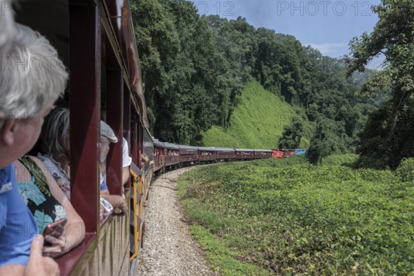 Great Smoky Mountains Railroad passengers looking out the windows of the open air train car while on an excursion from Bryson City, North Carolina