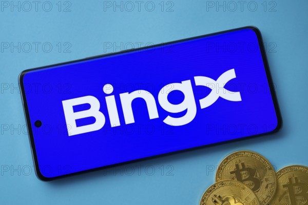 Smartphone displaying BingX logo with Bitcoin coins on a blue background