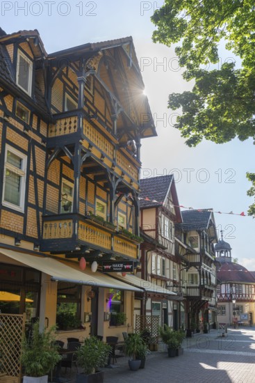 Half-timbered idyll of the old town of Bad Sooden, Allendorf, district Bad Sooden, townscape, restored gabled half-timbered houses with balcony, pedestrian zone for strolling, shops, restaurants, flower pots, tower of the Pfinnigstube, blue sky, clouds, backlight shot, Werra-Meissner-Kreis, Hesse, Germany