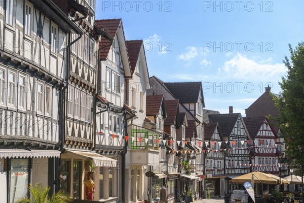 Half-timbered idyll of the old town of Bad Sooden, Allendorf, district Bad Sooden, townscape, restored gabled half-timbered houses with balcony, pedestrian zone for strolling, shops, sunshades, restaurants, blue sky, clouds, pennants, Werra-Meissner-Kreis, Hesse, Germany