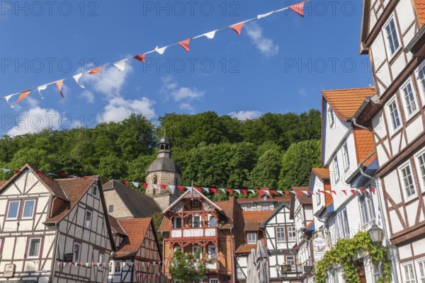 Half-timbered idyll of the old town of Bad Sooden, Allendorf, district Bad Sooden, townscape with Protestant St. Mary's Church, tower clock, forest, restored half-timbered houses, gabled houses, hillside location, blue sky, clouds, pennants, Werra-Meissner district, Hesse, Germany