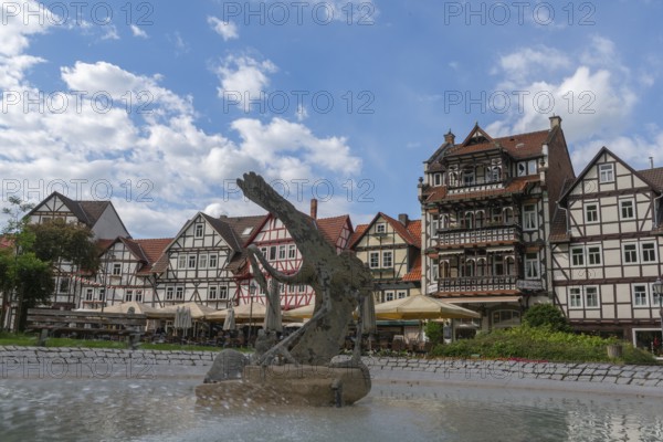 Half-timbered idyll of the old town of Bad Sooden, Allendorf, district Bad Sooden, townscape, restored half-timbered houses with balcony, gabled houses, fountain with artwork, sunshades, blue sky, clouds, Werra-Meissner-Kreis, Hesse, Germany